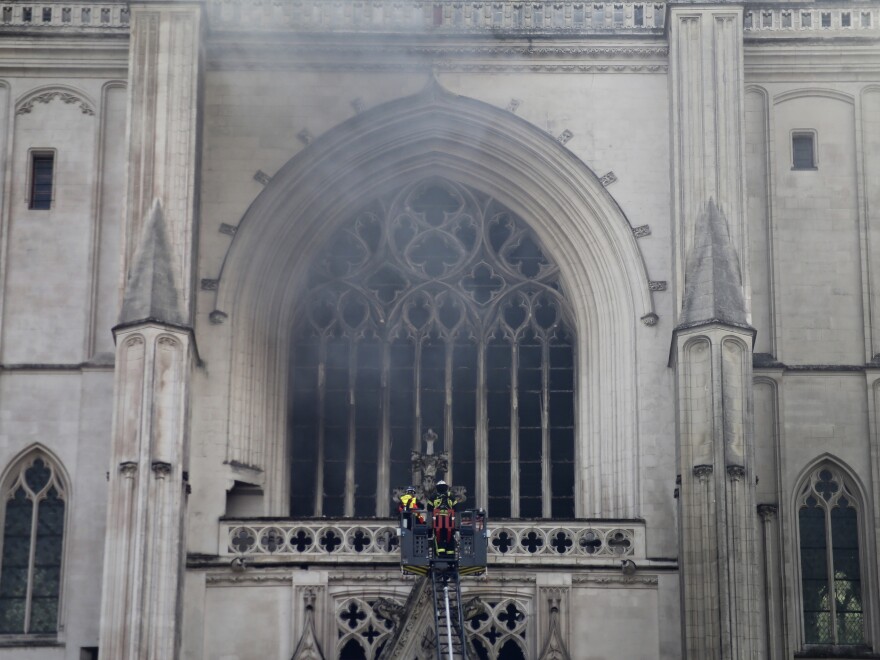 Firefighters work to extinguish the blaze at the Cathedral of St. Peter and St. Paul in Nantes on Saturday. The fire shattered stained-glass windows and sent black smoke billowing from between its two towers.