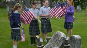 Blessed Sacrament students Dara Cassidy, Siobhan Armstrong, Molly Smith and Gracie Chesmore place flags on graves belonging to veterans at Cavalry Cemetery in Holyoke, Massachusetts.