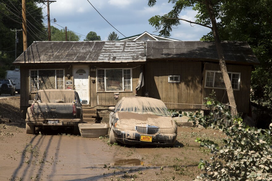 Muddy cars sit in front a flooded-out home on Saturday, June 25, 2016, in Clendenin, in northern Kanawha County, W.Va.