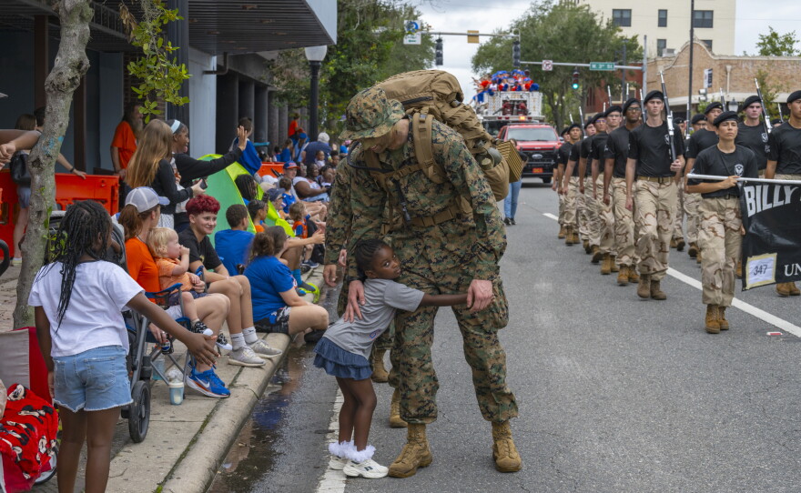 A child hugs a student in UF's Marine ROTC program during the University of Florida Homecoming parade Oct. 9, 2026, in Gainesville, Fla. (Andy Acosta/WUFT News)