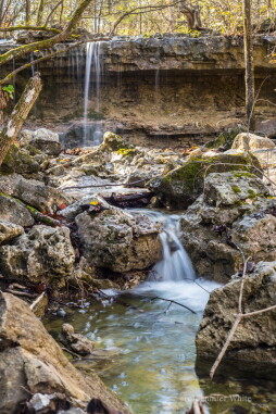 A view looking down a natural rain water creek at a couple waterfalls at Ruth and Paul Henning Conservation area in Branson, Missouri, United States. I took this during the autumn season. To see this, you have to hike off of the trail and into the woods. The waterfall in the back is the tallest one ine the park. There are many waterfalls there. Branson is also in the area known as the Ozarks.