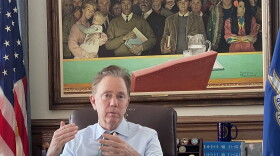 Gov. Ned Lamont. On the wall behind him is a Normal Rockwell original, "Right to Know."  