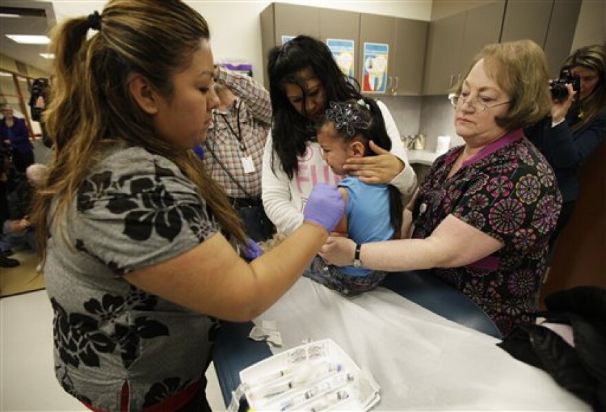 Nurses Fatima Guillen, left, and Fran Wendt, right, give Kimberly Magdeleno, 4, a Tdap whooping cough booster shot.