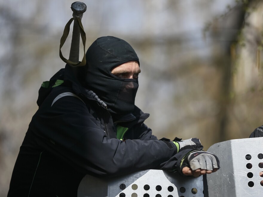 One of the pro-Russia protesters who have taken over the police headquarters in Slovyansk, Ukraine, watched from the barricades on Tuesday. Ukrainian authorities said special forces were beginning an operation against the demonstrators.