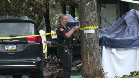 A police officer ties caution tape to a pole at the scene of a fatal house fire in Shavertown, Kingston Twp., Luzerne County on Wednesday, Aug. 5, 2026.