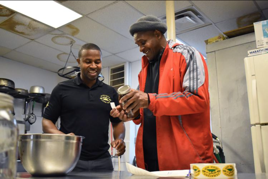 Rexroy Scott and Devon Francis prepare jars of Jerk Sauce on Feb. 7 at Jamaican Jerk Hut in Columbia. The sauce is homemade and unique to the Jerk Hut.