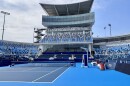 An empty blue tennis court surrounded by hundreds of vaulted seats