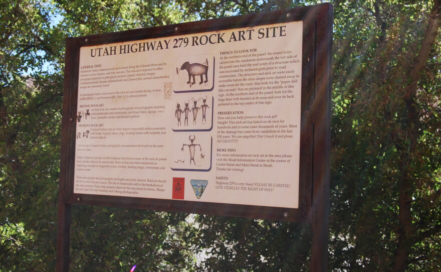 An interpretive sign at a highway pulloff tells visitors about the petroglyph panels on the canyon walls near Moab.