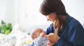 Young mother, kissing her newborn baby boy at home, mom and baby, embracing with love, emotional. Family concept