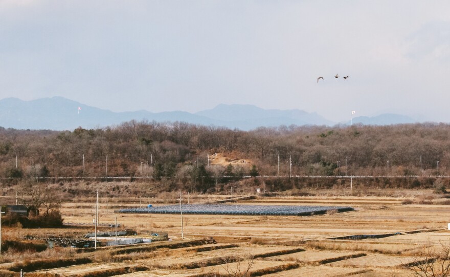 South Korea's Unification Village, Tongil Chon, sits within view of the North Korean border. Far into the distance to the left is a large North Korean flag in the village of Kijong-dong, North Korea. To the right is a South Korean flag in the border village of Daeseong-dong.