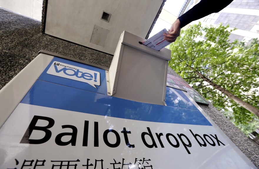 A voter drops a ballot into a ballot drop box Tuesday, Aug. 2, 2016, in Seattle.