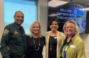 A man in a law enforcement uniform with three women to his right