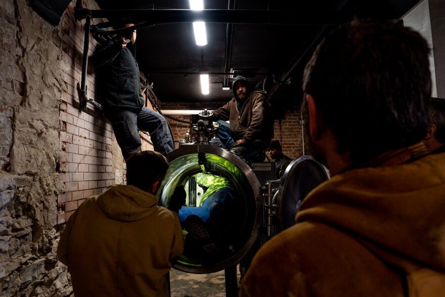 Kent Bourbon, 58, center, climbs into an Alkaline Hydrolysis machine in order to adjust the tank’s propellers on Friday, Jan. 5, 2024, at Hughes Funeral Alternatives at Hillcrest Abbey in Northampton.