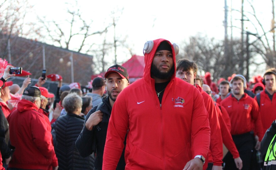 Fans and marching band members greet ISU football players and coaches