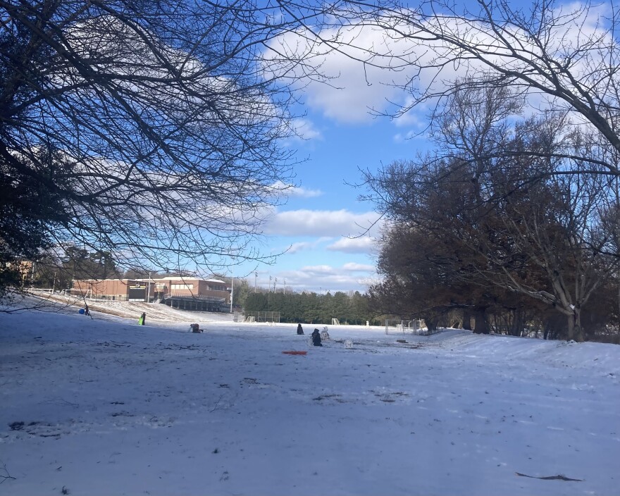 Children and families sled in the snow outside of a school in Winston-Salem, N.C. on Jan. 11, 2025. AMY DIAZ/WFDD