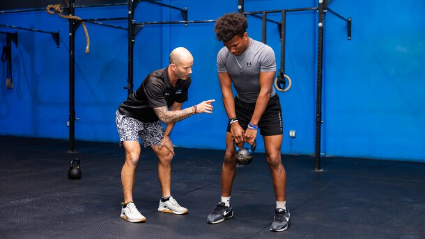 Coach Donnie Keller instructs a student of Wilson's Fit Futures in proper lifting technique.