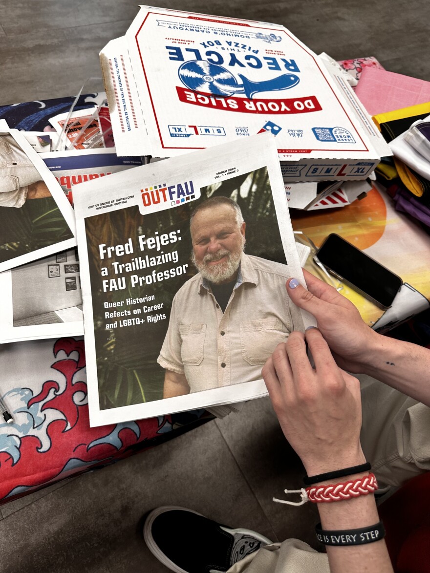 FAU student journalist Kenny Ruff flips through a recent edition of the new publication OutFAU, which was founded for and by LGBTQ students. The paper's small team has been working out of the old Center for IDEAs.