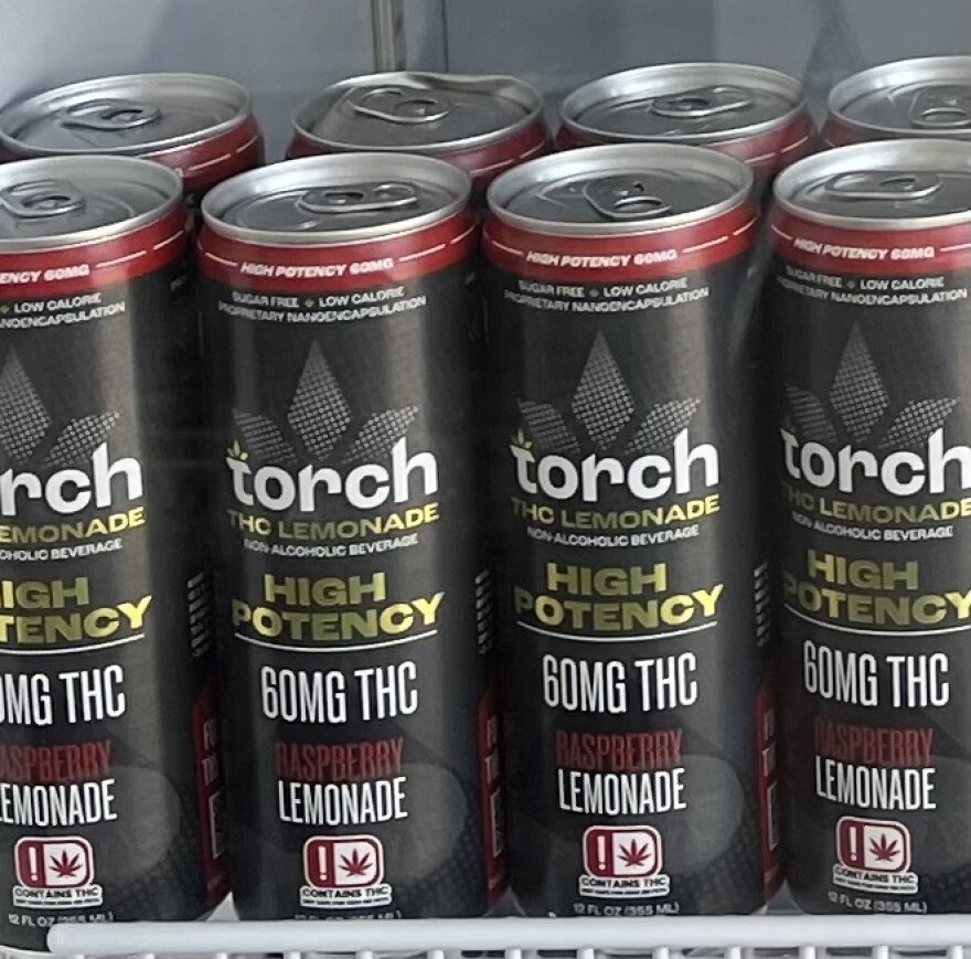Cans of Torch THC Lemonade line the shelf of a locked refrigerator at the front of Mary Jane CBD Dispensary.