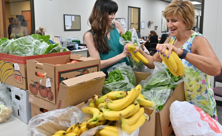 National Health Corps’ (NHC) Community Health Fellow Elsa Romero, left, and Darcie Schaffer, Volunteers in Medicine dental manager, package bags of fresh fruits and vegetables.