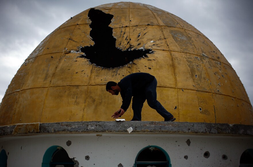 A Palestinian man picks up fragments of a mosque's golden dome, which was hit by a tank round during the fighting between Hamas and Israeli forces, north of Gaza City on Jan. 20, 2009.