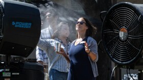 Christy Grady cools off in front of cooling fans during a University of Texas at Austin event in August of 2024 during a 107-degree day. 