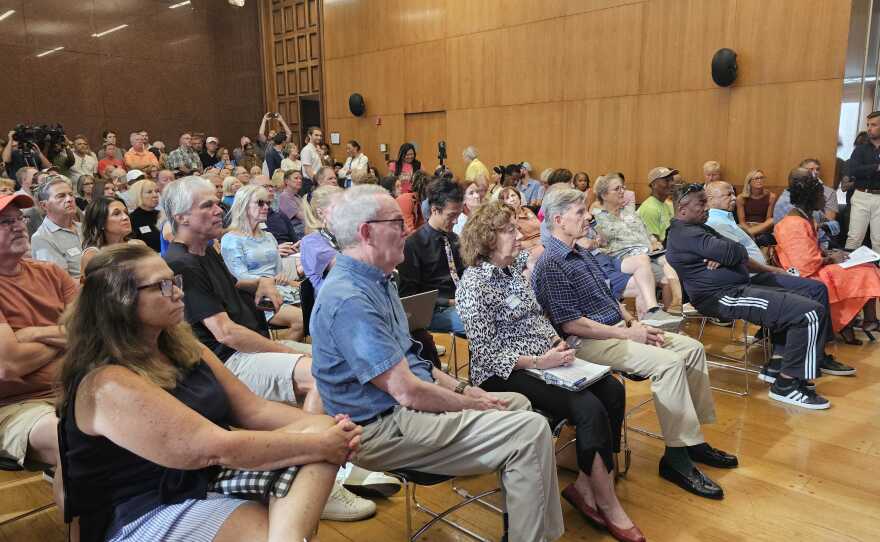 A meeting room full of people seated in chairs