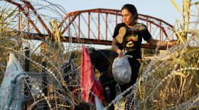 Eagle Pass, Texas, Saturday, September 23, 2023 - Lindy Peña of Venezuela braves razor wire in bare feet after wading across the Rio Grande and crossing the US/Mexico border.