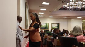 Carla Cunningham, wearing an orange vest over a black dress, holds her hand to open a door and exit the North Carolina House after crossing party lines to override the governor's veto of an immigration bill on Tuesday, July 29, 2025.