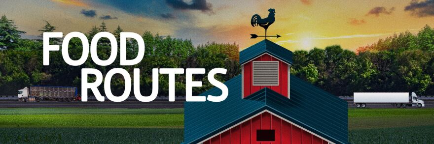 A graphic reads "Food Routes" on top of a field of corn. A chicken weather vane sits on top of a red barn, which is in front of a highway where two semi trucks drive.