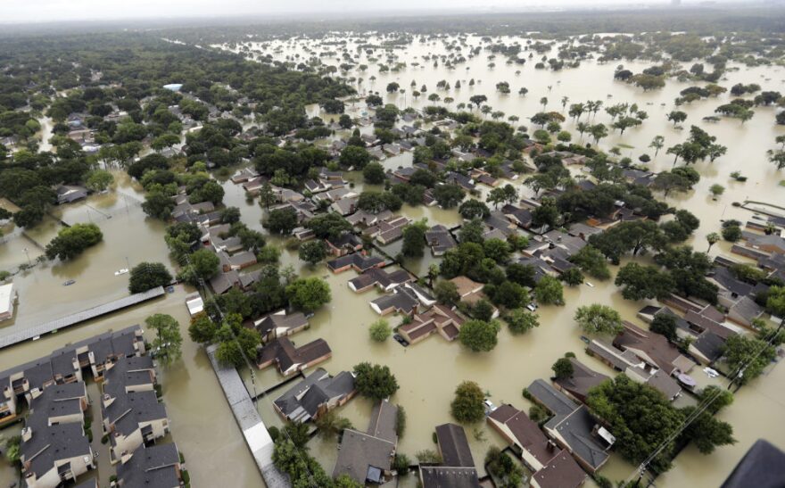 FILE - In this Aug. 29, 2017, file photo, water from Addicks Reservoir flows into neighborhoods from floodwaters brought on by Tropical Storm Harvey in Houston. Harris County commissioners have voted to ask the federal government for a $17 million grant to purchase 104 homes at the highest risk of flooding. The decision came even as more than 1,000 residents have called the Flood Control District in recent days to request buyouts of their Hurricane Harvey flood-damaged homes. (AP Photo/David J. Phillip, File)