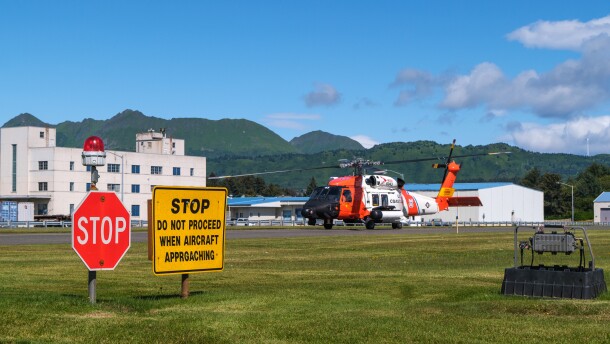 A Coast Guard rescue helicopter lands on the runway in Kodiak before it parks near an air station hangar.