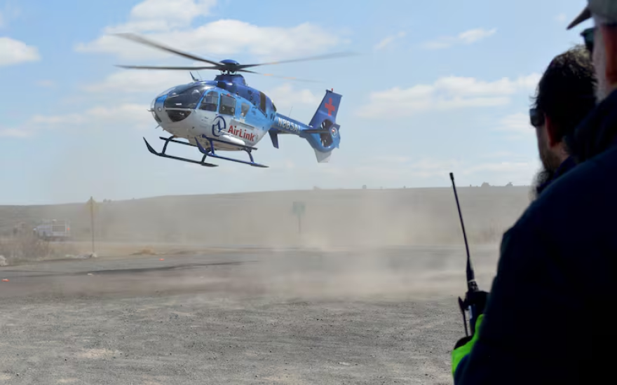 An air ambulance kicks up dust as it lands.