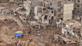 Rescuers and relatives sit in front of collapsed buildings after recent flooding in Libya. (Muhammad J. Elalwany/AP)
