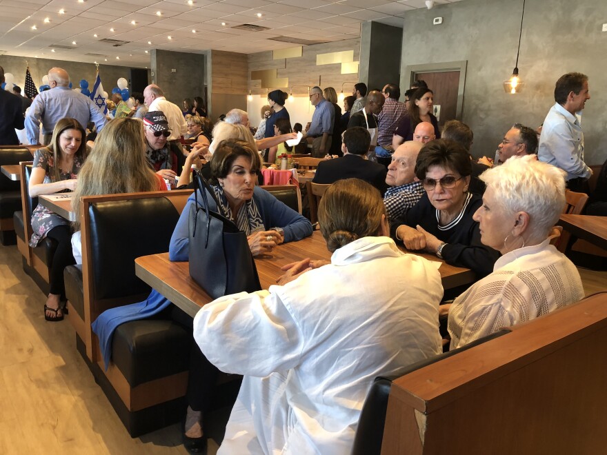 People sat at diner tables and ate sandwiches and fruit at Mo's Bagels and Deli in Aventura before the campaign event for DeSantis.