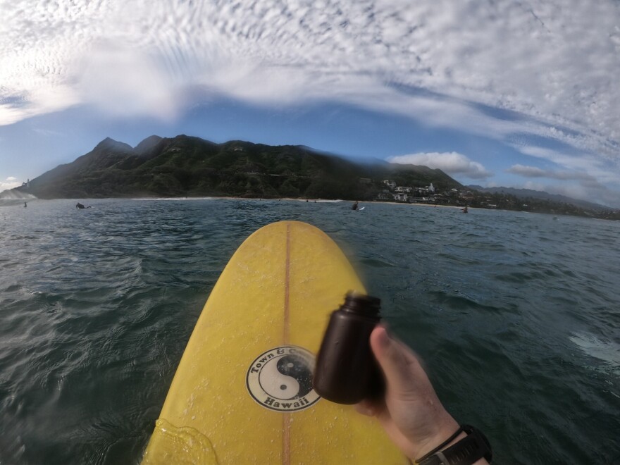 A volunteer holds a water sample collected while out surfing near Lēʻahi.