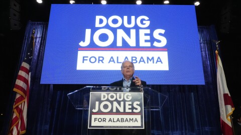 Gubernatorial candidate former Sen. Doug Jones stands behind a podium in front of a screen reading "Doug Jones for Alabama" during an event Friday, Dec. 12, 2025, in Birmingham, Alabama.