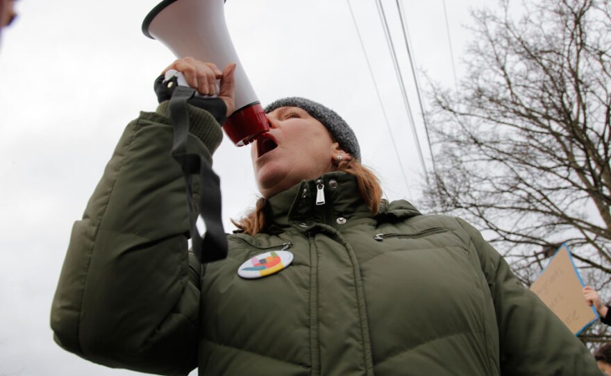 Leslie Brown, an activist with Edmonds Neighborhood Action Coalition, shouted into a bullhorn to rally dozens of protesters gathered outside the Edmonds PCC, January 29, 2017. 