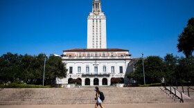 A student walks in front of UT Austin's tower in the fall.