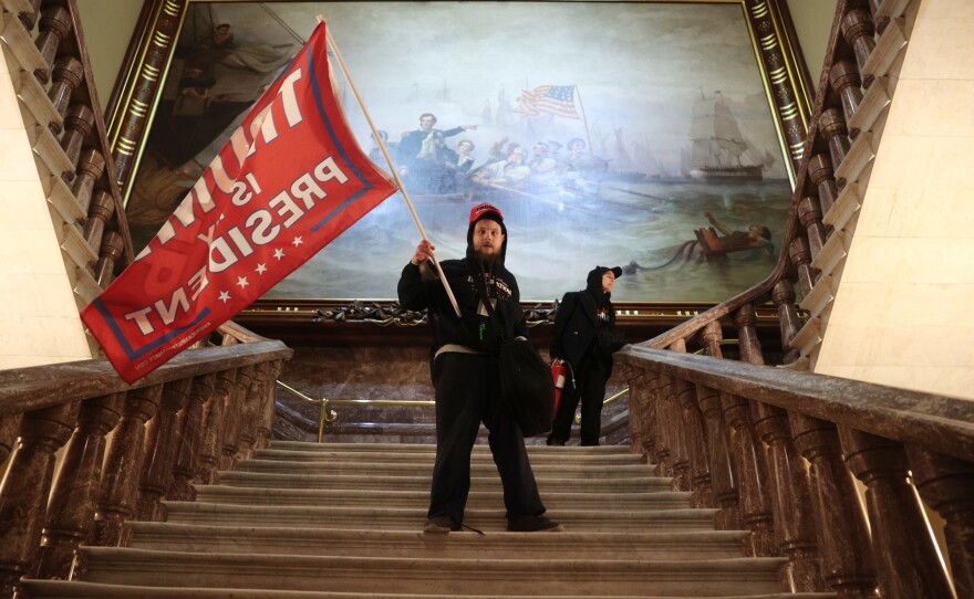 A rioter holds a Trump flag inside the U.S. Capitol Building near the Senate Chamber.