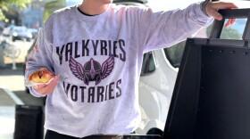 Natasha Dantzing serves up a free hot dog with onions and peppers at a tailgate party she and her wife organized before the Valkyries' first playoff home game on September 27, 2026.