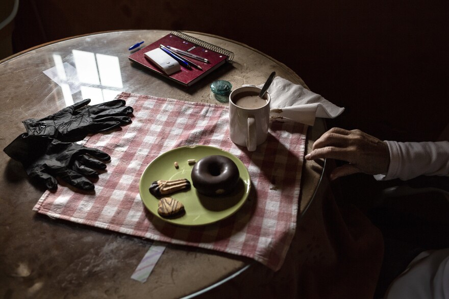 José Aguilera, 84, eats his breakfast at his home in Seville. Protective gloves are part of the new landscape of the everyday life.