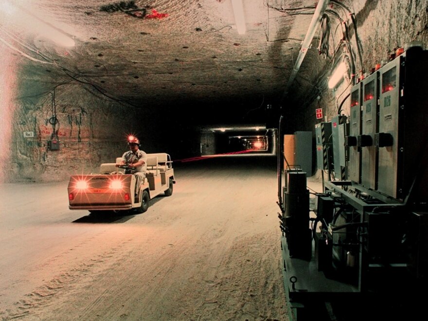 A worker drives an electric cart past air monitoring equipment inside a storage room of the Waste Isolation Pilot Plant in Carlsbad, N.M., shown in this undated photo.