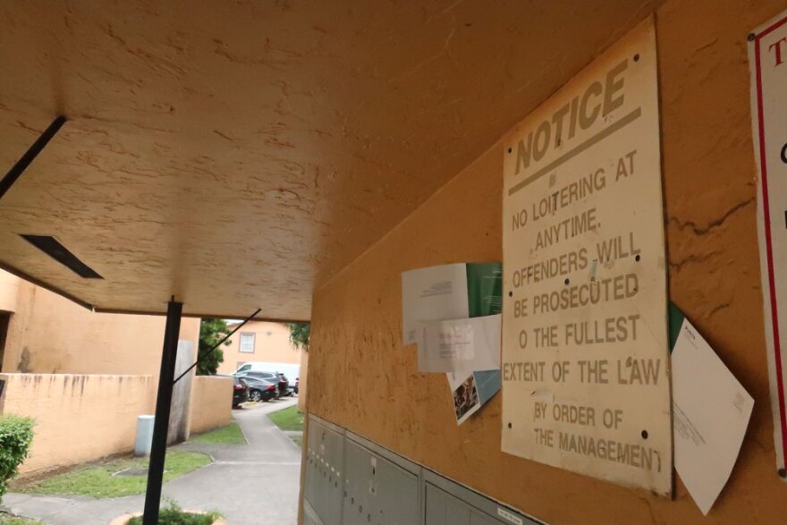 Letters wedged between a sign and a concrete wall above a row of broken mailboxes.