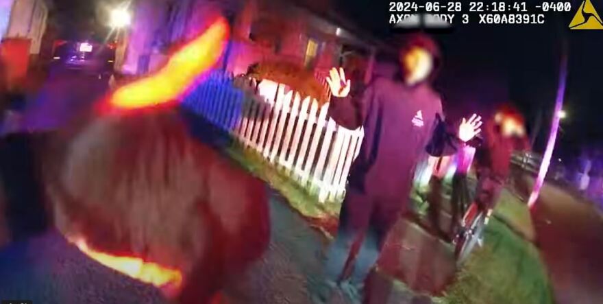 In this screenshot from a police-worn body camera, an officer talks to a group of teens. they later ran and one, Nyah Mway, was shot and killed.