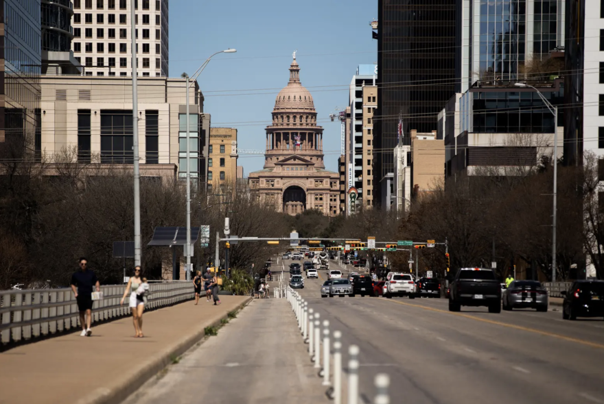 Pedestrians walk across the South Congress bridge with the Capital in the background in Austin on March 3, 2021. 