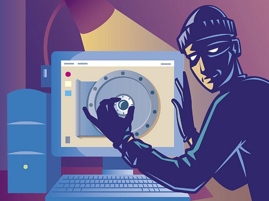 An internet hacker dressed as a robber cracks a code on a desktop