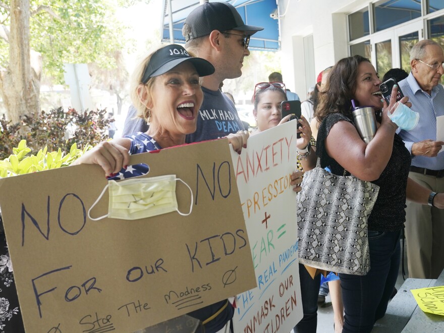 Joann Marcus (left) cheers as she listens to the Broward County School Board's emergency meeting last month in Fort Lauderdale, Fla. A small but vocal group spoke vehemently against masks, saying their personal rights were being eroded and their children were suffering socially.