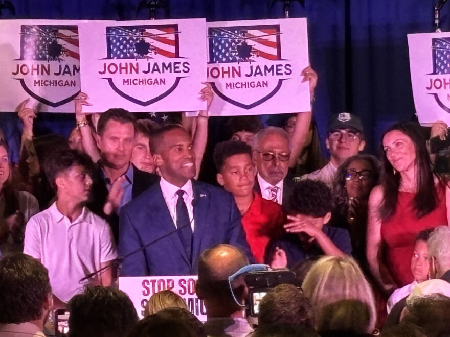 A monochromatic photo of Jocelyn Benson is in front of a purple to red gradient background. To the left is the Michigan Public Election 2026 Results logo. Underneath are the words "John James" and "Republican Gubernatorial Primary."