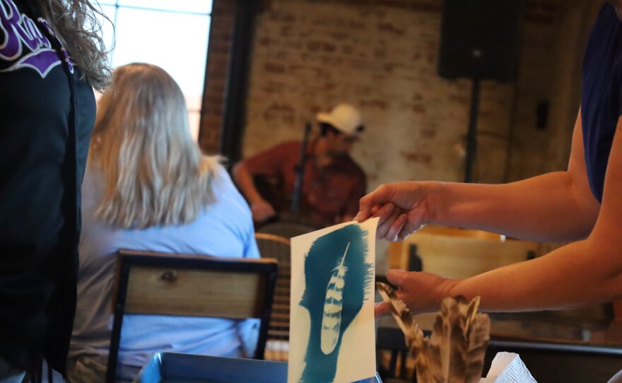 Andi Keidl shows guests of the art walk the results of their cyanotype print. Photo by Allison Diaz.