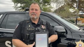 Oklahoma County Sheriff's Deputy Gene Bradley holds an iPad designed to help people in crisis. The iPads connect Oklahomans to virtual counseling resources.